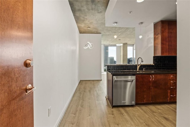 kitchen featuring dishwasher, a sink, light wood-style floors, dark countertops, and baseboards