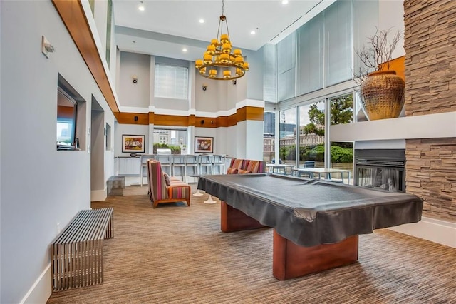 recreation room with a towering ceiling, a chandelier, billiards, a fireplace, and baseboards