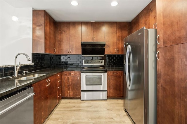 kitchen featuring stainless steel appliances, a sink, light wood-type flooring, decorative backsplash, and recessed lighting