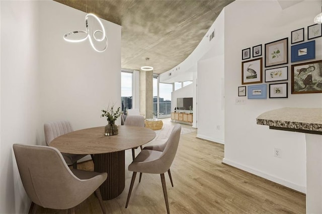 dining space with light wood finished floors, baseboards, and floor to ceiling windows