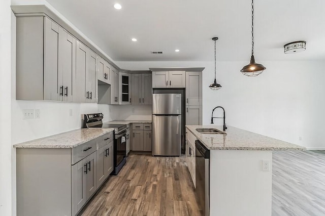 kitchen featuring gray cabinets, visible vents, appliances with stainless steel finishes, wood finished floors, and a sink