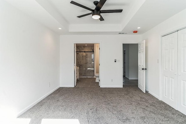 unfurnished bedroom with visible vents, baseboards, a raised ceiling, a closet, and dark carpet