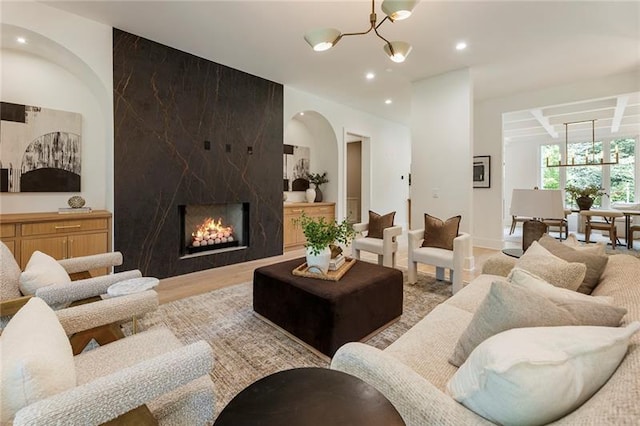 living room with a large fireplace, light hardwood / wood-style flooring, and an inviting chandelier