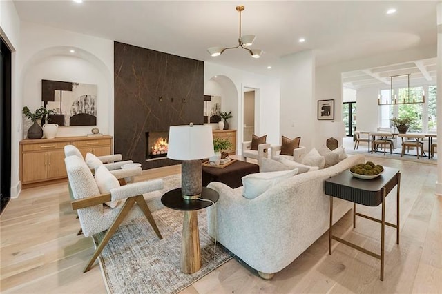 living room with a premium fireplace, light hardwood / wood-style floors, and a notable chandelier