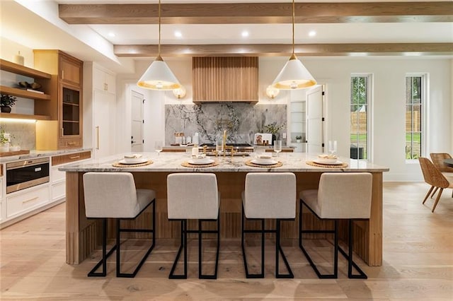 kitchen with decorative light fixtures, white cabinetry, and a breakfast bar area