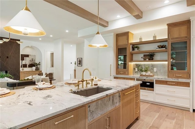 kitchen featuring light stone countertops, sink, hanging light fixtures, light hardwood / wood-style floors, and white cabinets