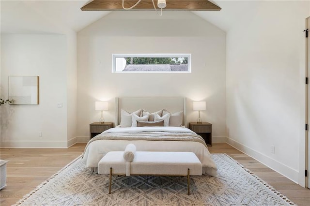 bedroom with vaulted ceiling with beams and light hardwood / wood-style flooring