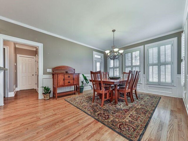 535 Crested Hawk Rdg, Canton, GA 30114 - dining area featuring light wood finished floors, an inviting chandelier, a decorative wall, crown molding, and wainscoting