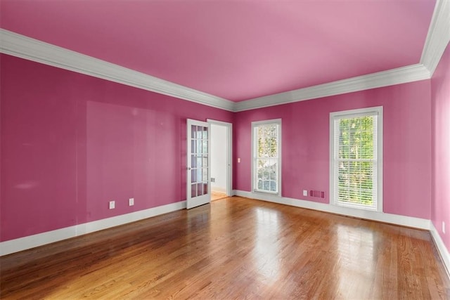 empty room with french doors, crown molding, visible vents, wood finished floors, and baseboards