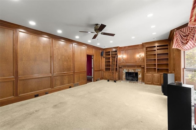 unfurnished living room featuring carpet floors, ornamental molding, a high end fireplace, and a decorative wall