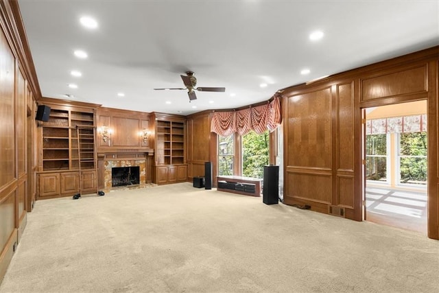 unfurnished living room featuring light colored carpet, a premium fireplace, crown molding, wood walls, and recessed lighting