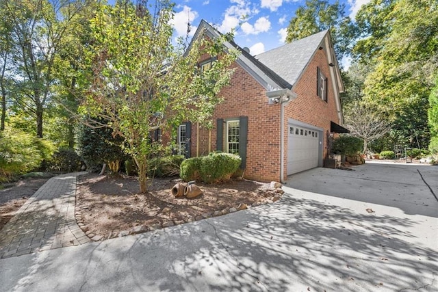 view of front of home featuring a garage, concrete driveway, and brick siding