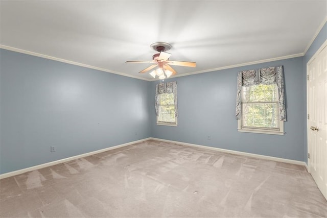 carpeted empty room with a ceiling fan, baseboards, and crown molding