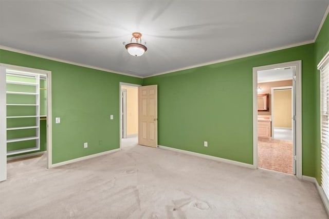 unfurnished bedroom with ornamental molding, carpet flooring, a walk in closet, and baseboards