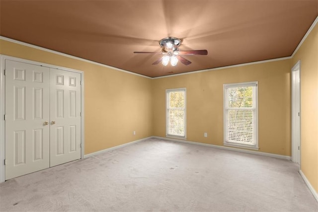 unfurnished bedroom with carpet, a closet, ornamental molding, a ceiling fan, and baseboards