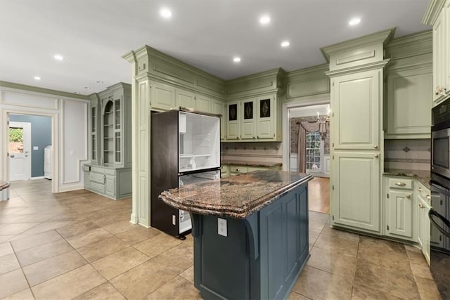 kitchen with recessed lighting, freestanding refrigerator, a center island, tasteful backsplash, and dark stone countertops