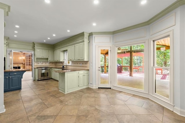 kitchen featuring crown molding, stainless steel stove, decorative backsplash, a sink, and a peninsula