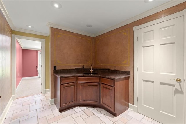 kitchen featuring dark countertops, ornamental molding, brown cabinetry, and a sink