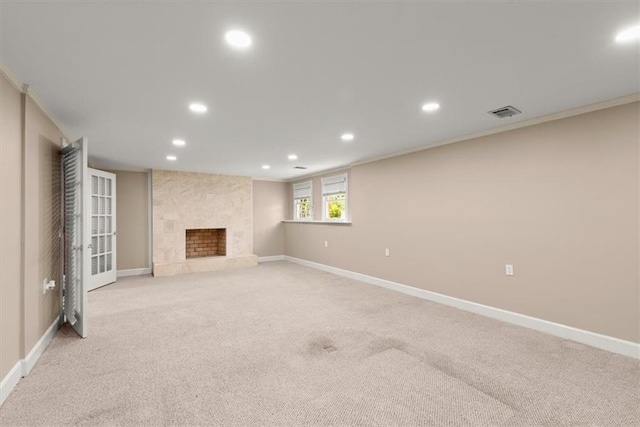 unfurnished living room featuring recessed lighting, a large fireplace, light carpet, baseboards, and crown molding