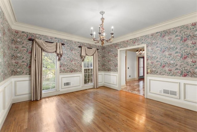 unfurnished dining area featuring wallpapered walls, visible vents, and wainscoting