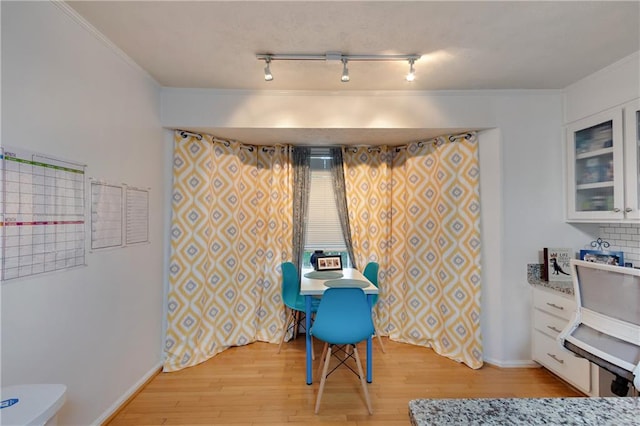 interior space featuring light hardwood / wood-style flooring, track lighting, and ornamental molding