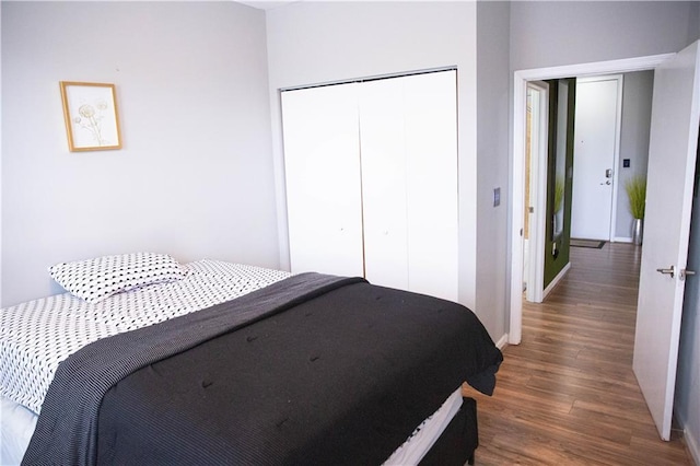 bedroom featuring dark wood-style floors, a closet, and baseboards