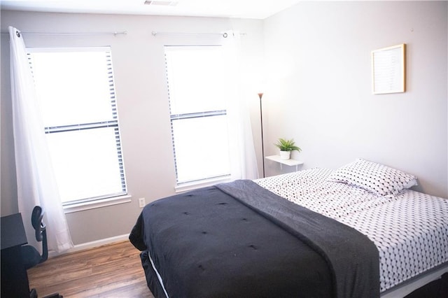 bedroom featuring wood finished floors, visible vents, and baseboards