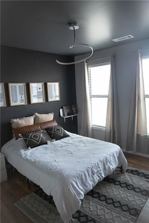 bedroom featuring multiple windows, wood finished floors, and visible vents