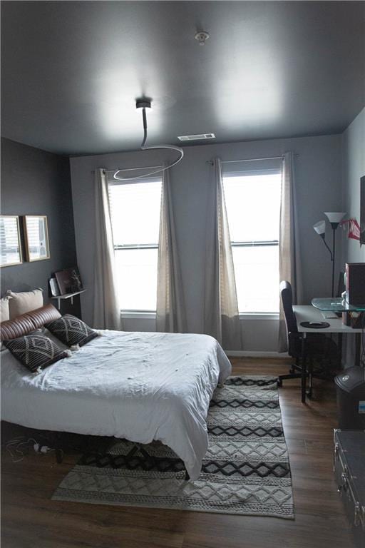 bedroom featuring dark wood-style floors, multiple windows, and visible vents