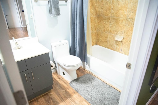 bathroom with toilet, shower / bathtub combination with curtain, wood finished floors, and vanity