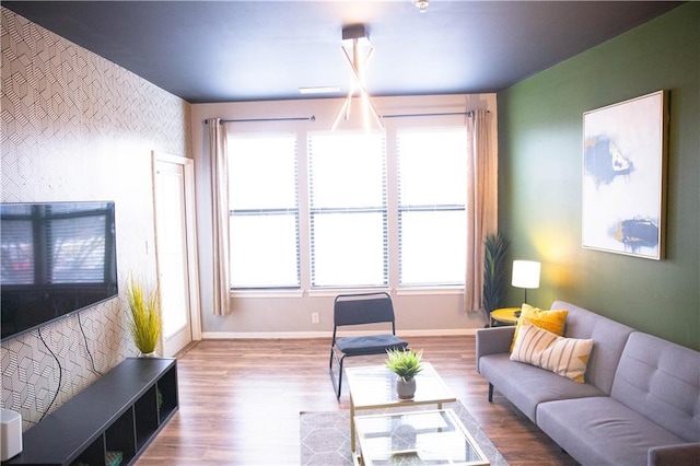living room featuring light wood-style flooring, an accent wall, and baseboards