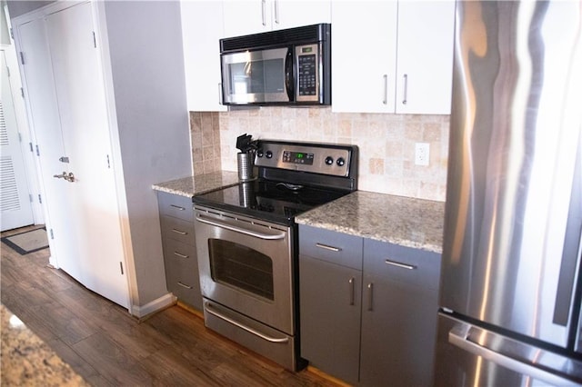 kitchen with stone countertops, gray cabinetry, dark wood-type flooring, white cabinetry, and appliances with stainless steel finishes