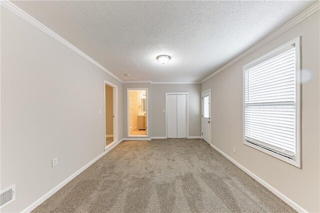 unfurnished room with visible vents, baseboards, ornamental molding, a textured ceiling, and light carpet