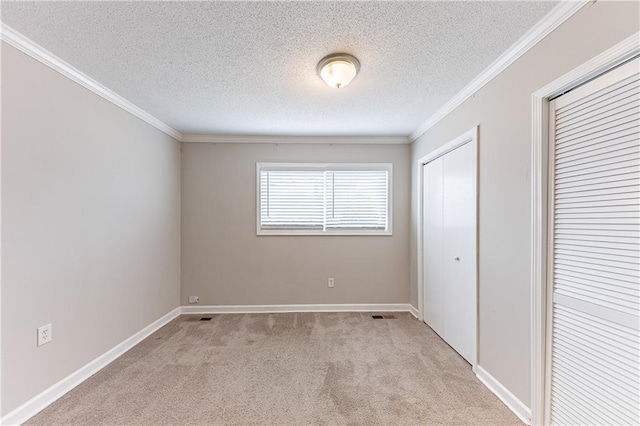 unfurnished bedroom with visible vents, baseboards, ornamental molding, a textured ceiling, and light carpet