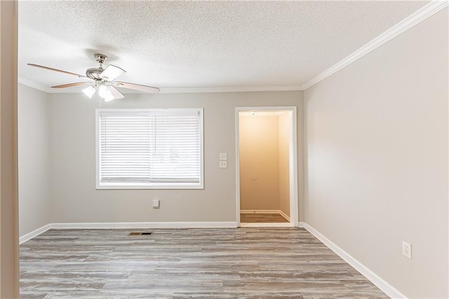 spare room with baseboards, a textured ceiling, wood finished floors, and ornamental molding