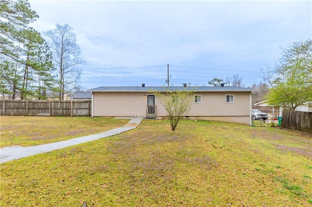back of house with a lawn and fence