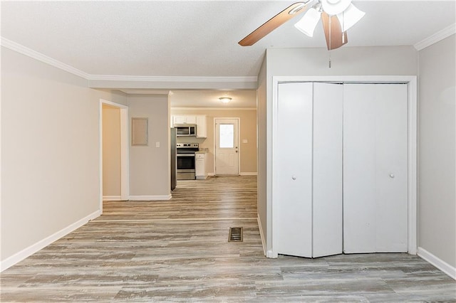 interior space featuring baseboards, visible vents, light wood finished floors, and ornamental molding