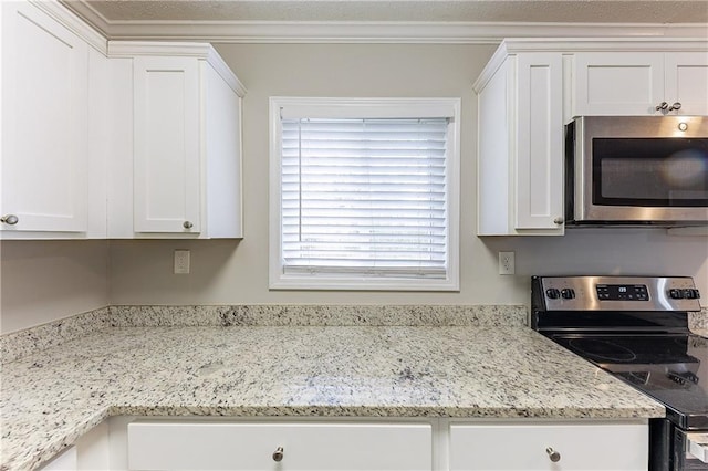 kitchen with white cabinetry, stainless steel appliances, crown molding, and light stone countertops