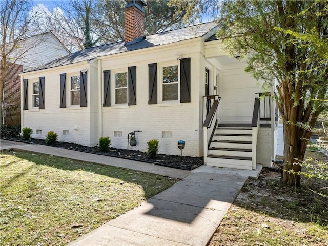 view of home's exterior featuring entry steps, brick siding, crawl space, a lawn, and a chimney