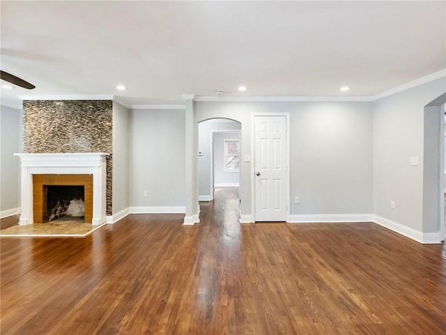 unfurnished living room with ornamental molding, arched walkways, and wood finished floors