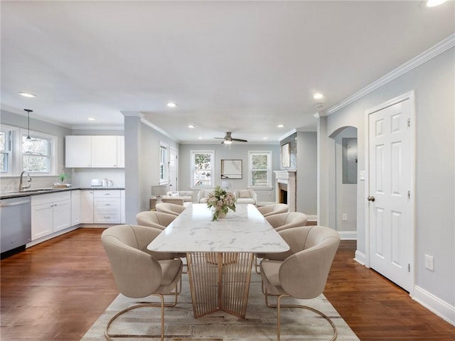 dining space with ornamental molding, dark wood-style flooring, a fireplace, and baseboards