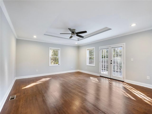 empty room with visible vents, dark wood finished floors, a tray ceiling, and french doors