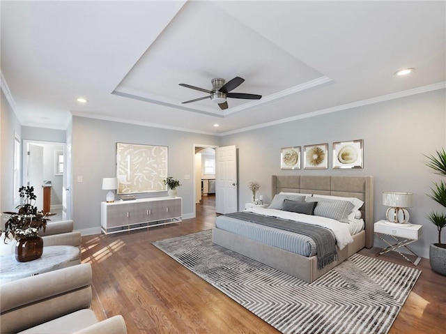 bedroom featuring baseboards, a tray ceiling, wood finished floors, and ornamental molding