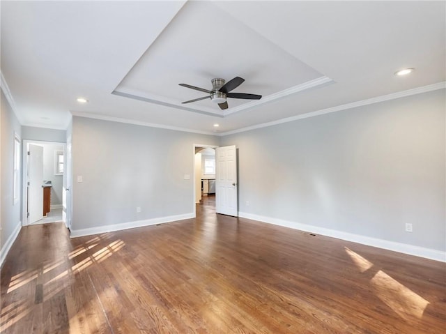 empty room with a tray ceiling, recessed lighting, a ceiling fan, wood finished floors, and baseboards