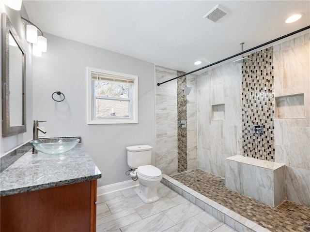 full bathroom featuring toilet, visible vents, a tile shower, and vanity