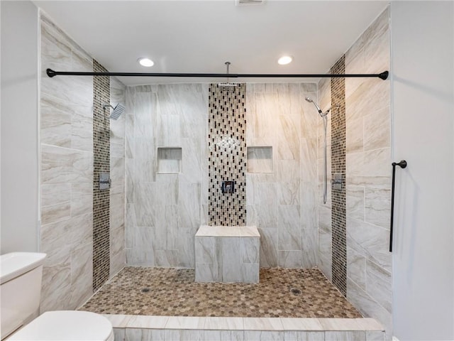 bathroom featuring toilet, tiled shower, and recessed lighting