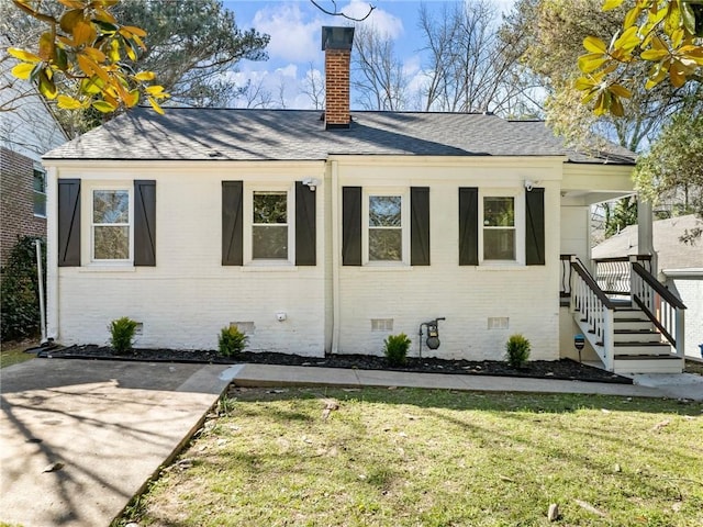 view of property exterior featuring brick siding, crawl space, a chimney, and a lawn