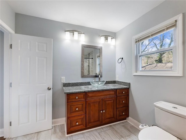 bathroom with a shower, baseboards, vanity, and toilet