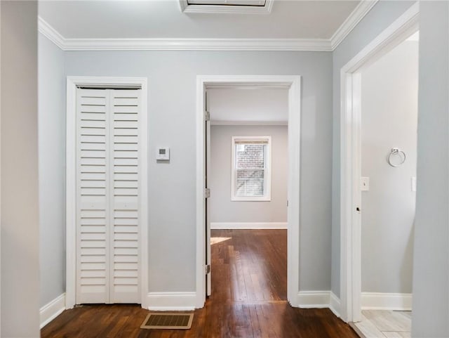 hall featuring crown molding, dark wood-type flooring, visible vents, and baseboards