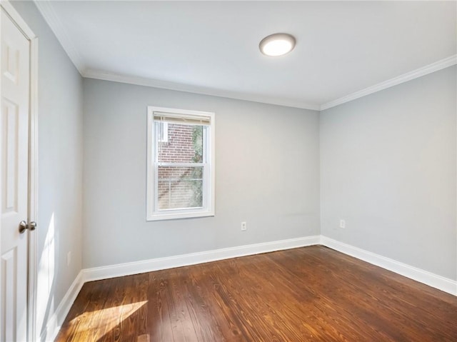 spare room with dark wood-type flooring, ornamental molding, and baseboards